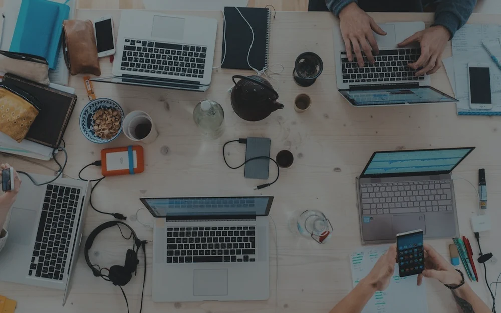Foto eines Arbeitstisches mit Laptops und digitalen Arbeitswerkzeugen